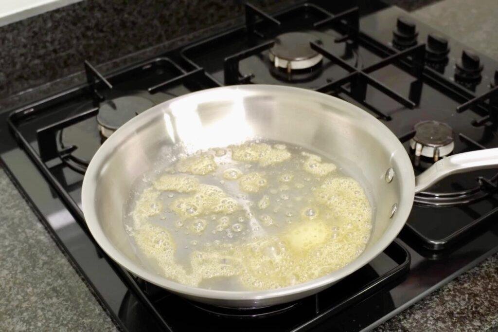 Butter and garlic melting in a steel pan on a gas hob