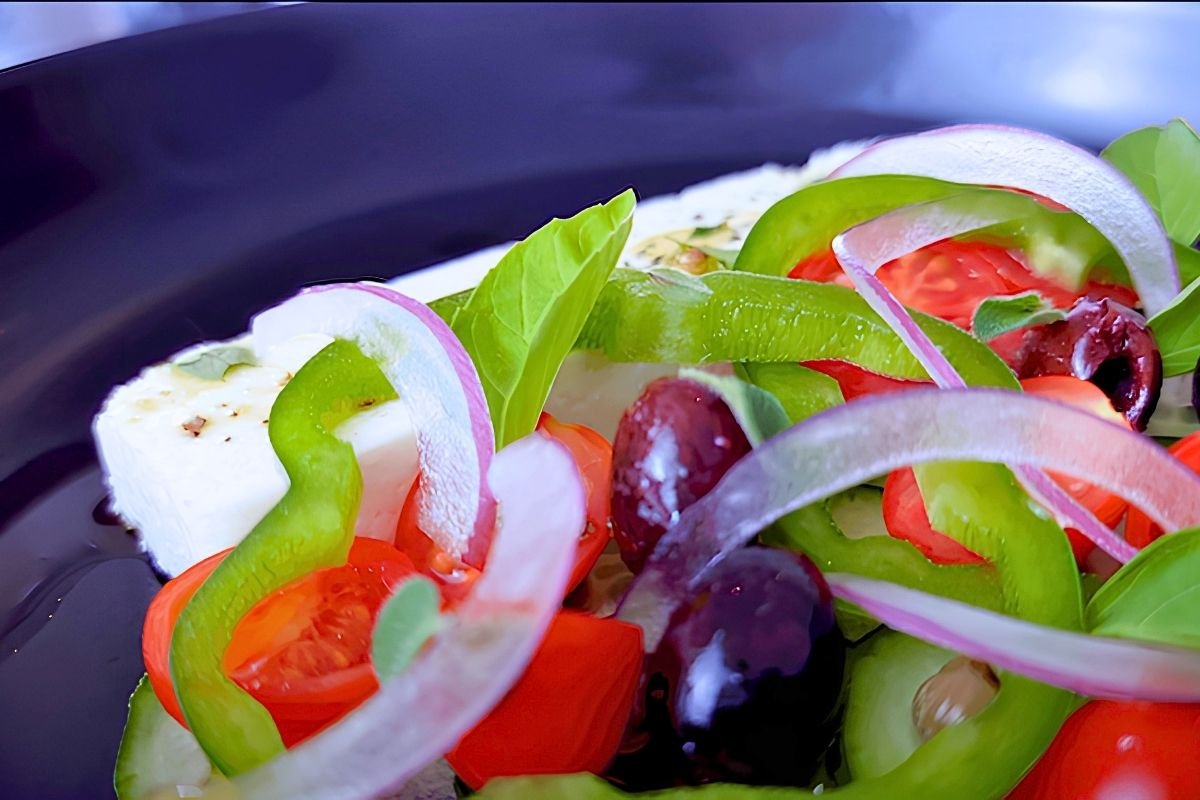 Close up of Greek salad with green pepper, red onion slices, olives and tomato