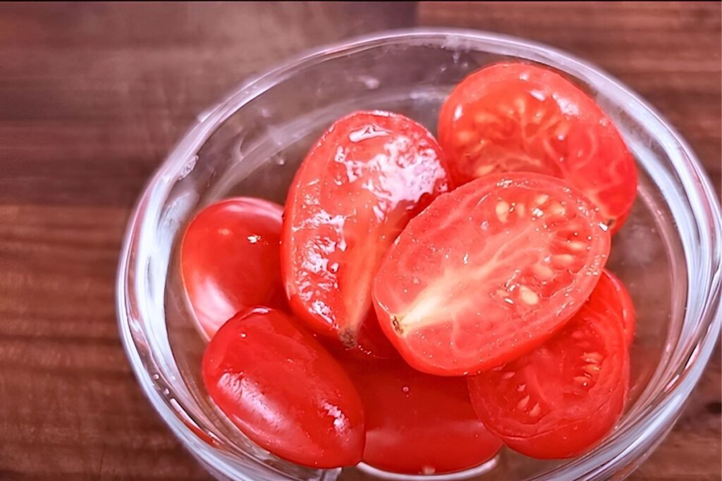 Glass bowl of halved ripe tomatoes