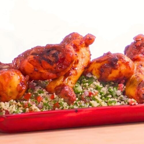 Glazed chicken drumsticks served over tabbouleh on a red platter