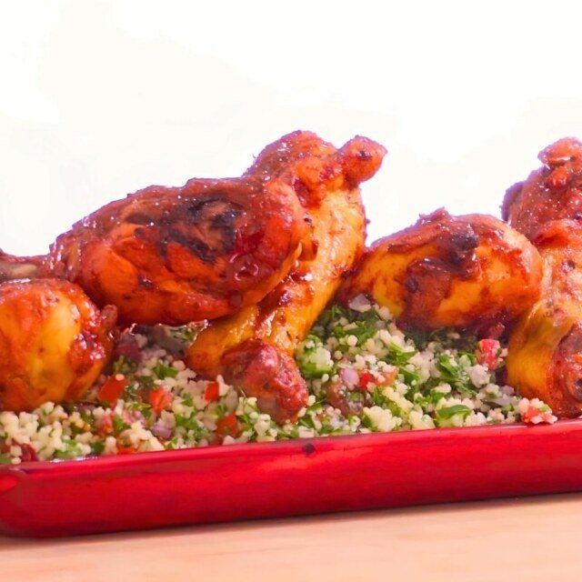 Glazed chicken drumsticks served over tabbouleh on a red platter