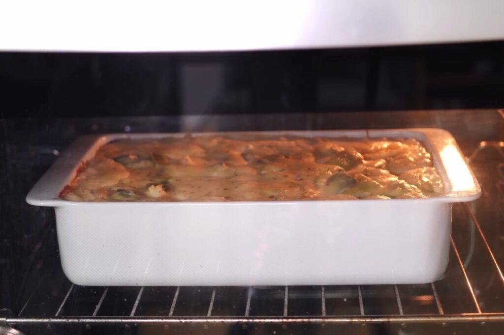 Bubbling golden leek gratin in a white dish in the oven