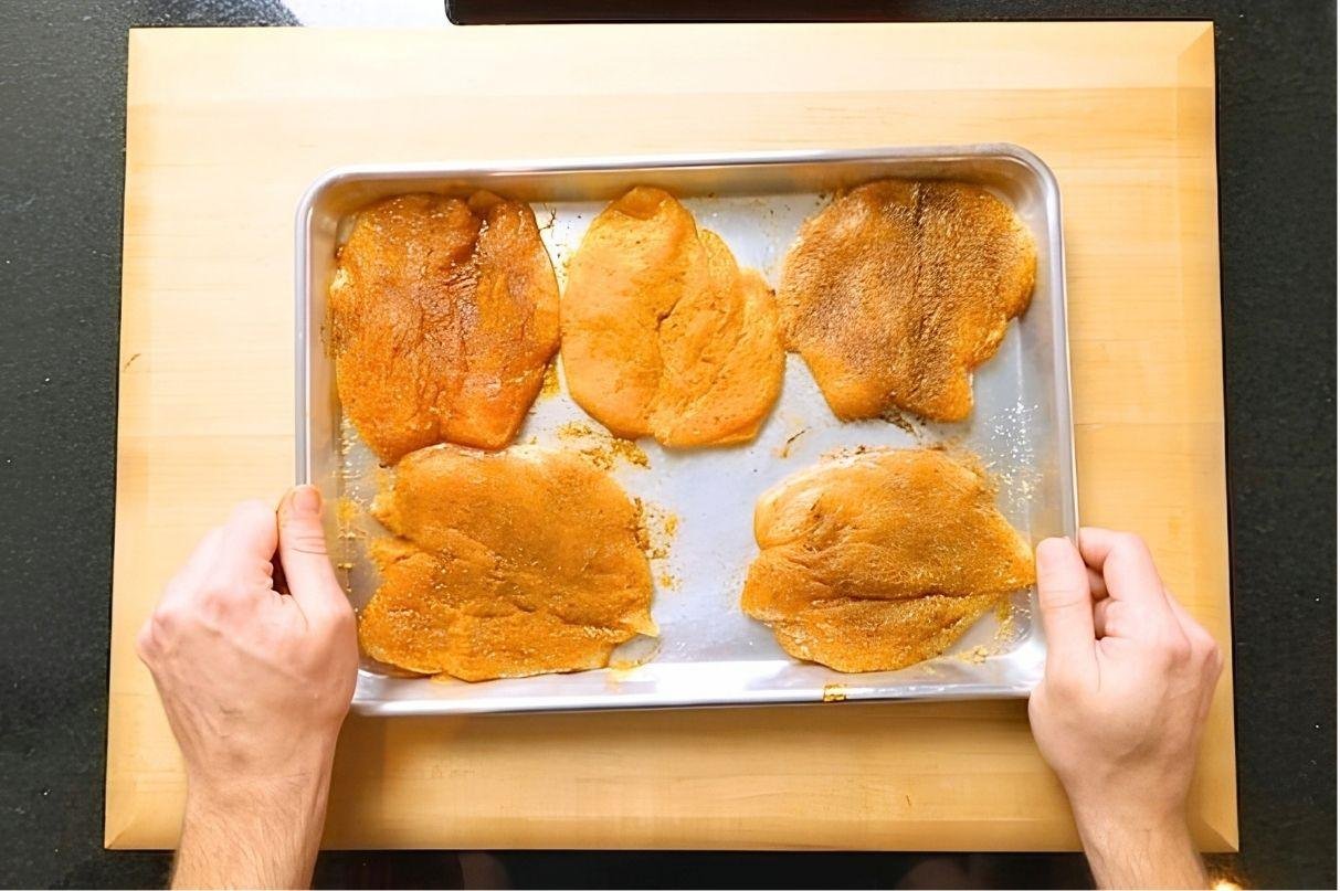 chicken breasts marinating on a tray