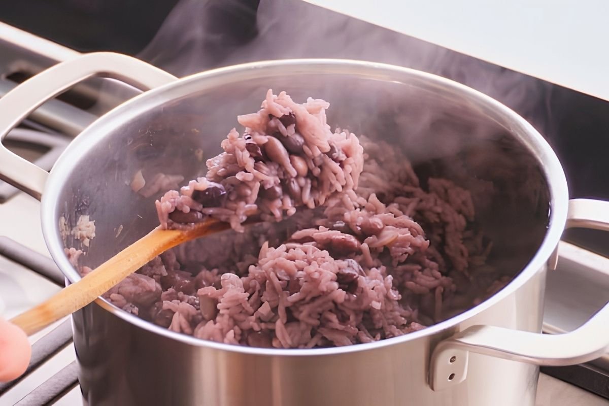 Saucepan of moros y cristianos, black beans and rice, steaming on the hob