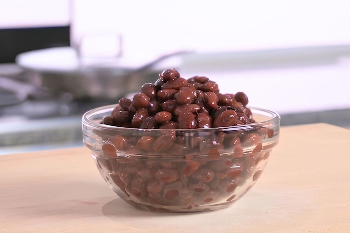 Glass bowl of cooked black beans on a wooden board