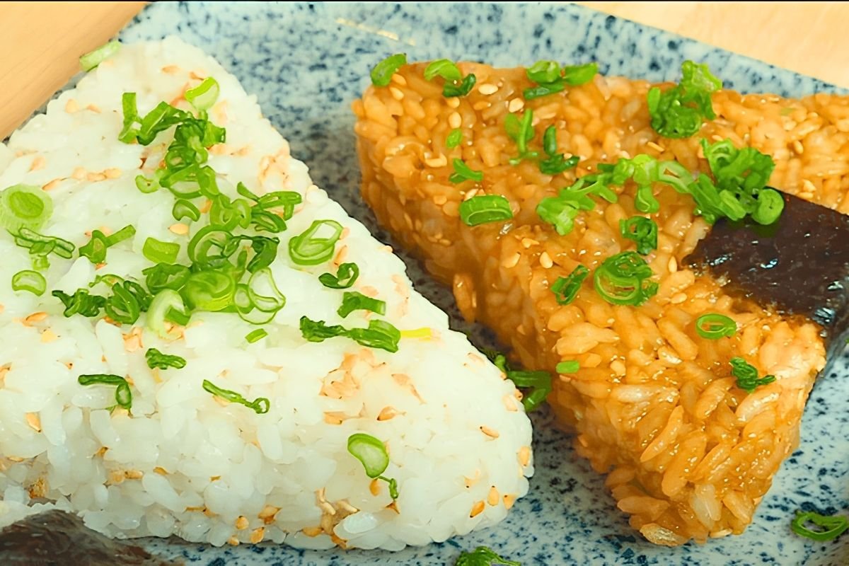 Close up of a plain onigiri with spring onion beside a soy glazed onigiri with nori
