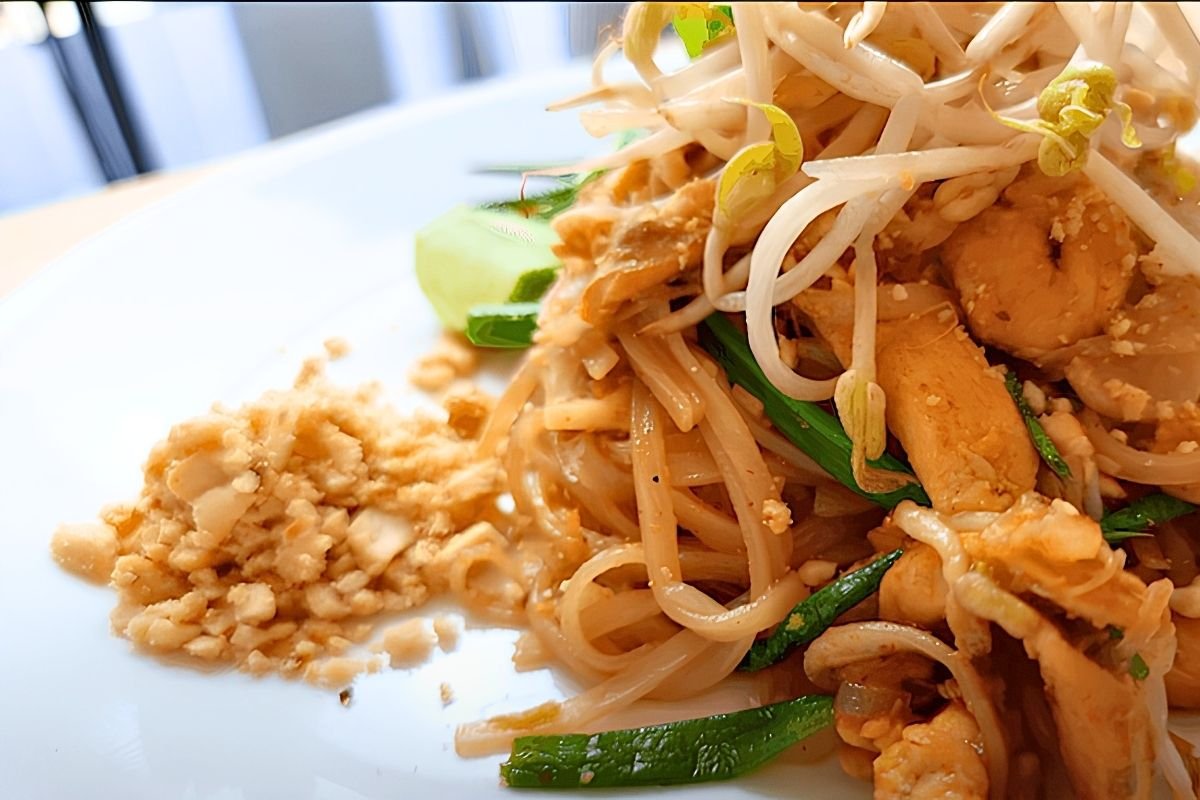 Close up of chicken pad thai with bean sprouts, chives and crushed peanuts