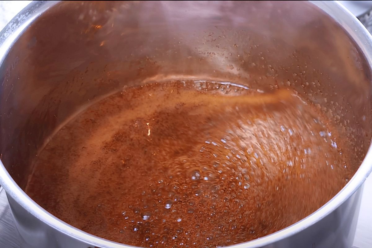 Dark brown pad thai sauce bubbling in a steel pan