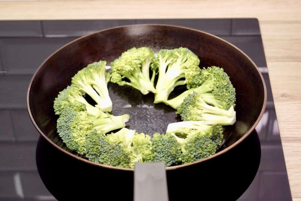 Broccoli florets arranged cut side down in a ring around the edge of a frying pan