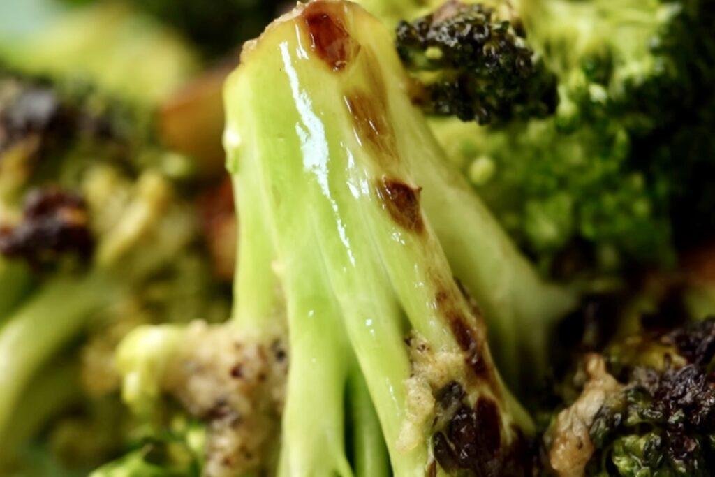 Close up of a charred broccoli floret with a golden brown cut stalk and vibrant green top