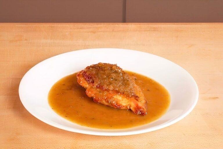 chicken breast on a plate with pan sauce