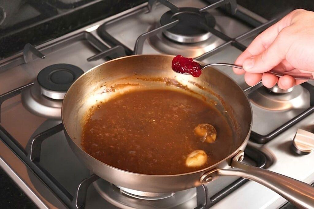 redcurrant jelly being added to a pan sauce