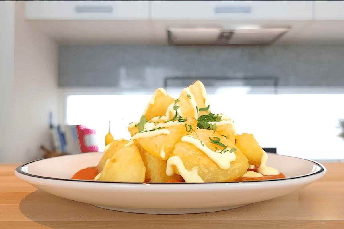 Plate of patatas bravas with spicy tomato sauce, aioli and chopped parsley