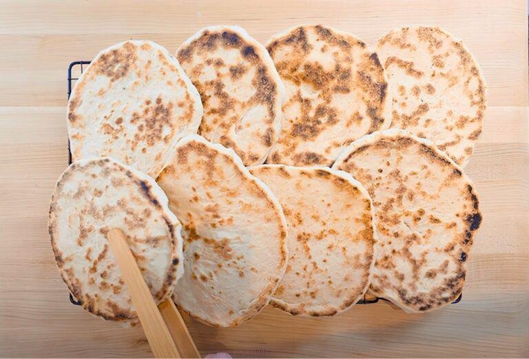 Overhead view of a stack of cooked pitta breads on a wooden board