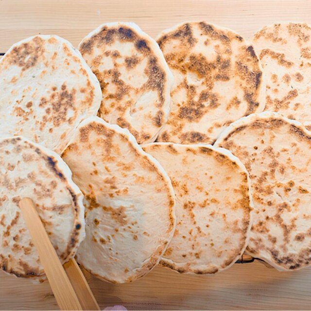 Overhead view of a stack of cooked pitta breads on a wooden board