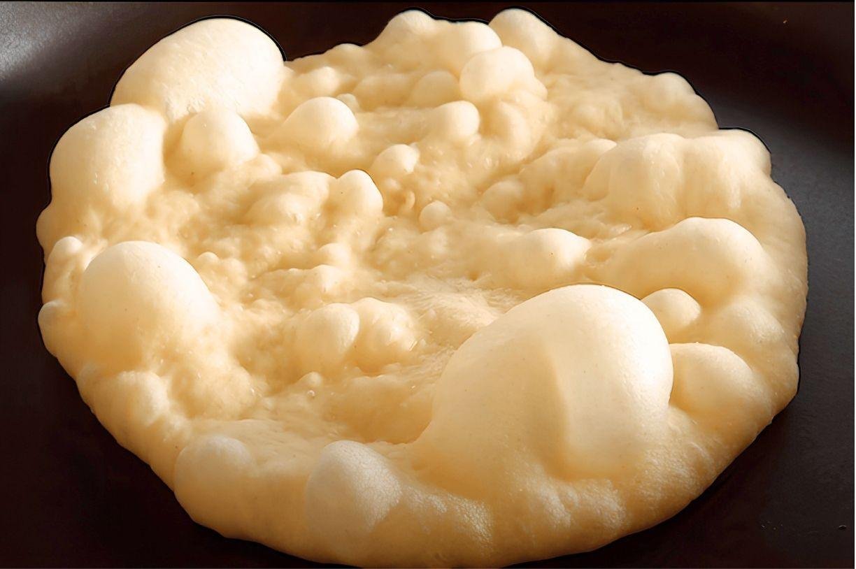 Close up of a pitta bread puffing up in a pan