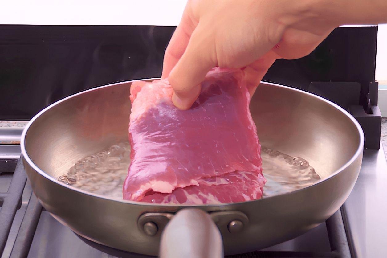 pork belly being simmered in a pan of water