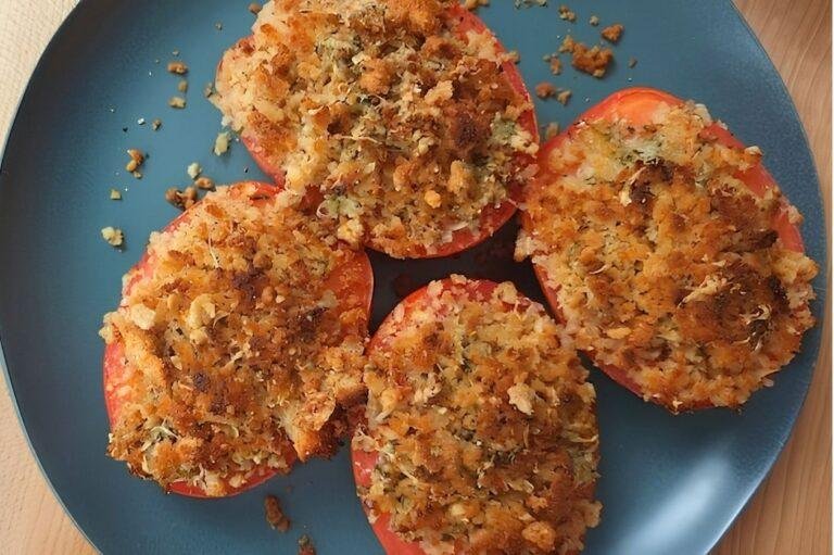 Baked Garlic Tomatoes topped with a crispy Parmesan and herb crust, served on a blue plate.