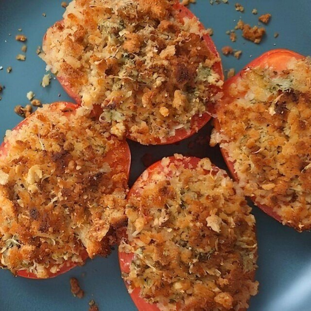 Baked Garlic Tomatoes topped with a crispy Parmesan and herb crust, served on a blue plate.