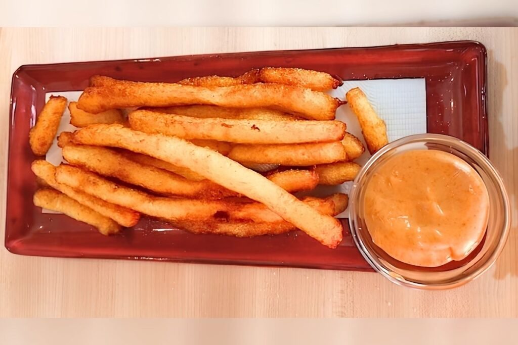 Crispy golden fries served on a red platter with a side of creamy dipping sauce, perfect for the ultimate fries recipe.