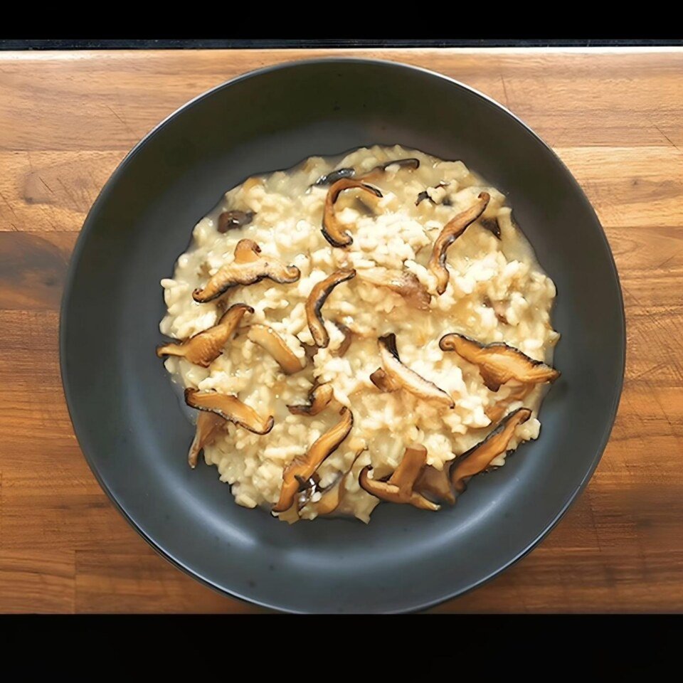 overhead shot bowl of mushroom risotto on a dark wooden chopping