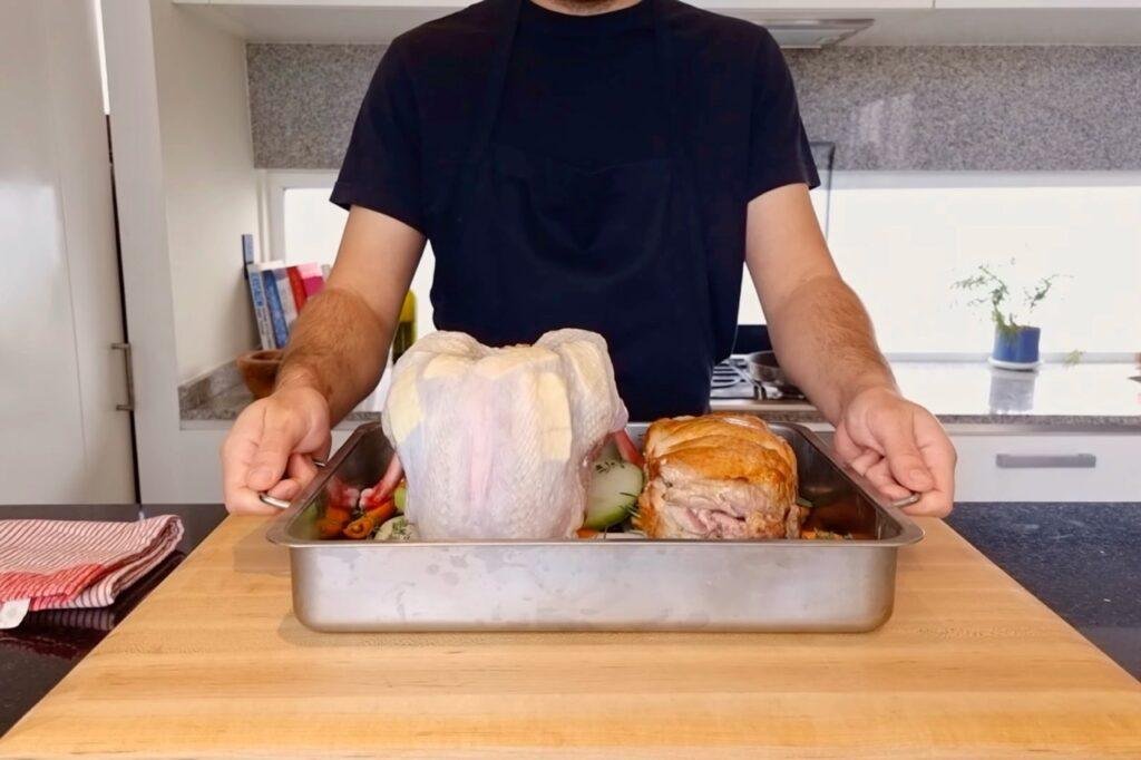 Person holding a roasting tin with raw and roasted turkey pieces