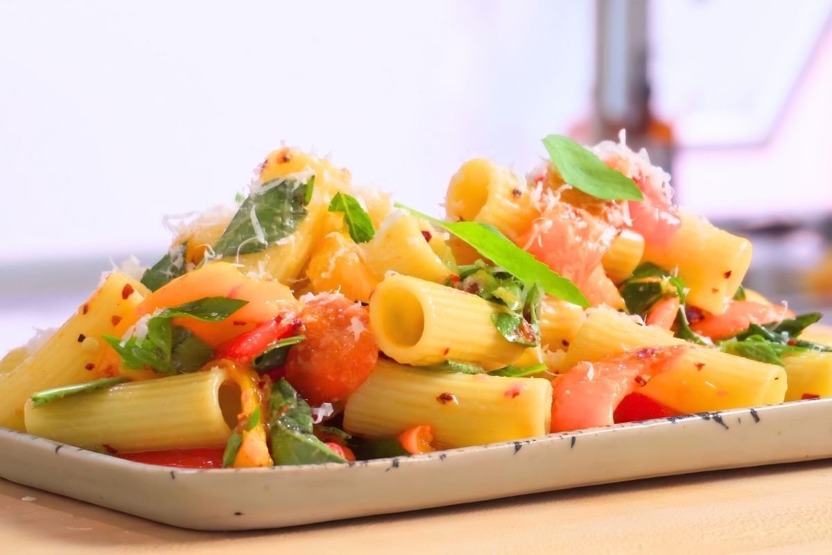 Rigatoni pasta salad with roasted peppers, basil and parmesan on a ceramic platter