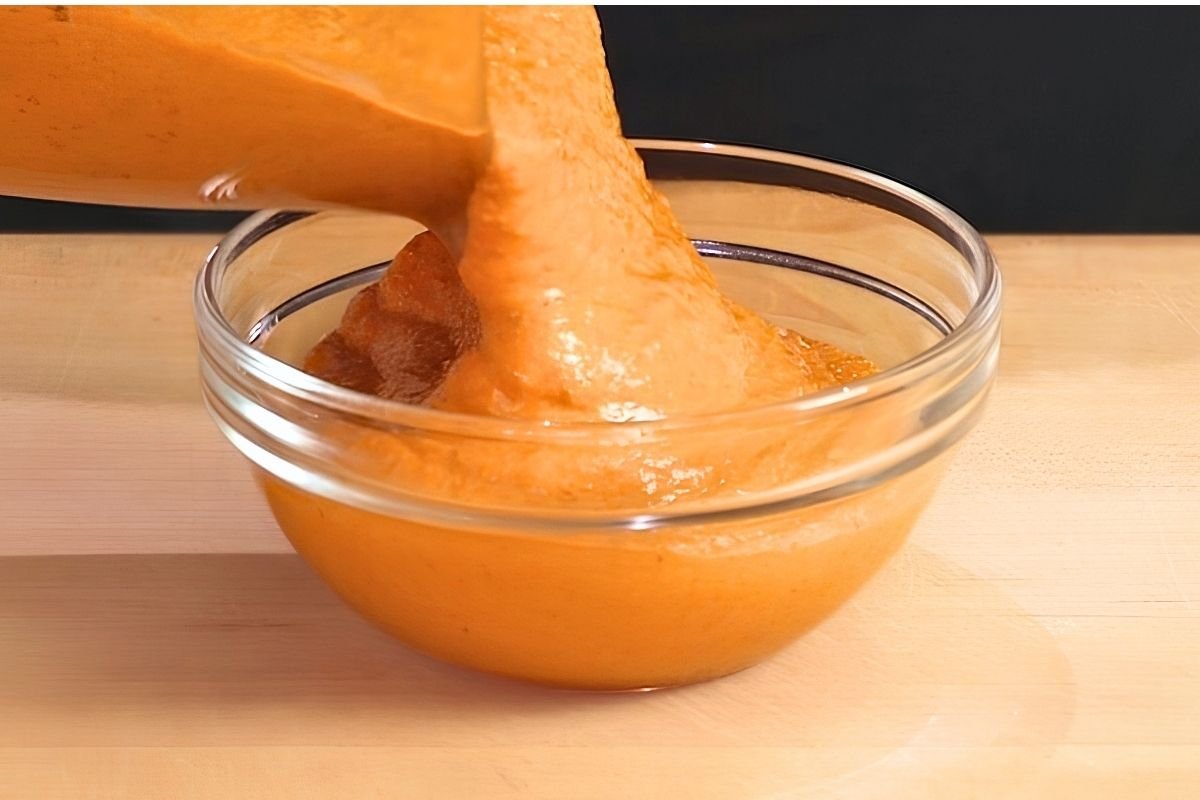 Romesco sauce being poured from a blender into a glass bowl
