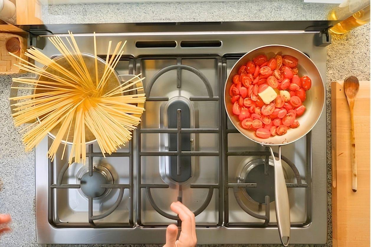 spaghetti being cooked in salted water on a stove top