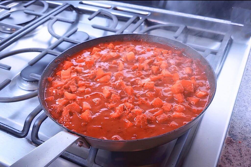 Pan of chunky tomato sauce simmering on the hob for shakshuka