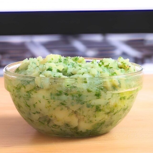 Glass bowl of skordalia, a mashed potato and garlic dip with chopped fresh herbs