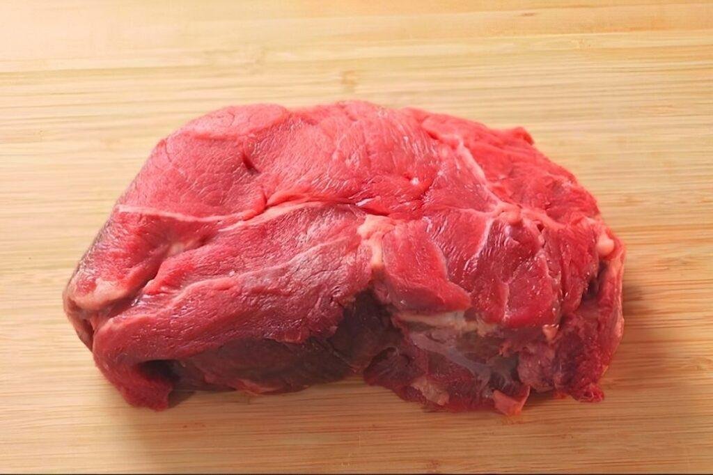 raw chuck steak on a chopping board