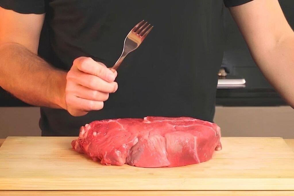 tenderising steak with a fork