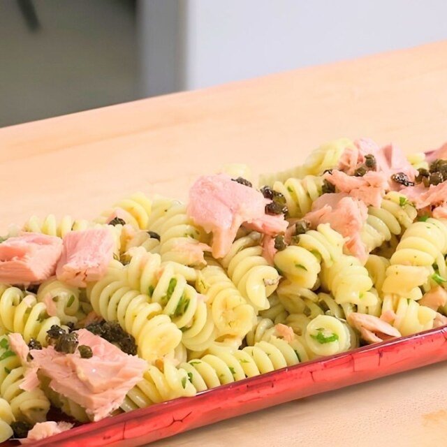 Red platter of fusilli pasta salad with flaked tuna and crispy capers