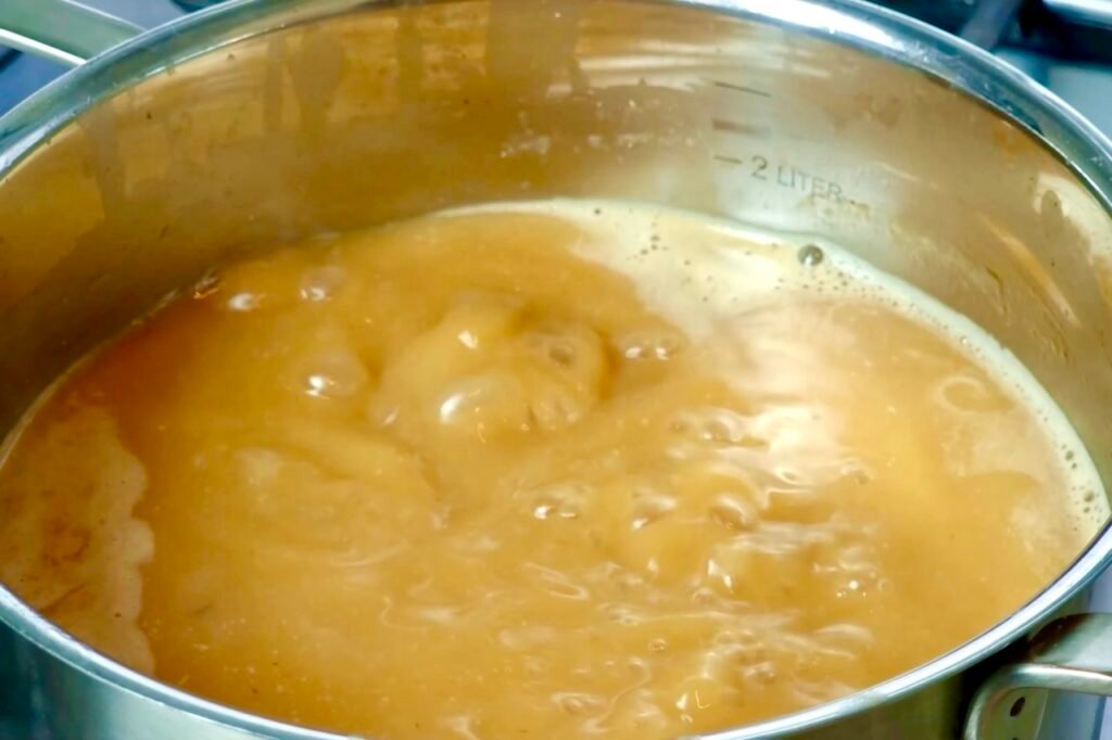 Bubbling golden brown gravy in a large steel pot