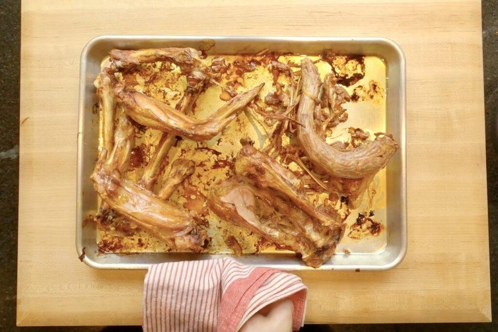 Roasted turkey wings and bones on a baking tray beside a striped oven cloth