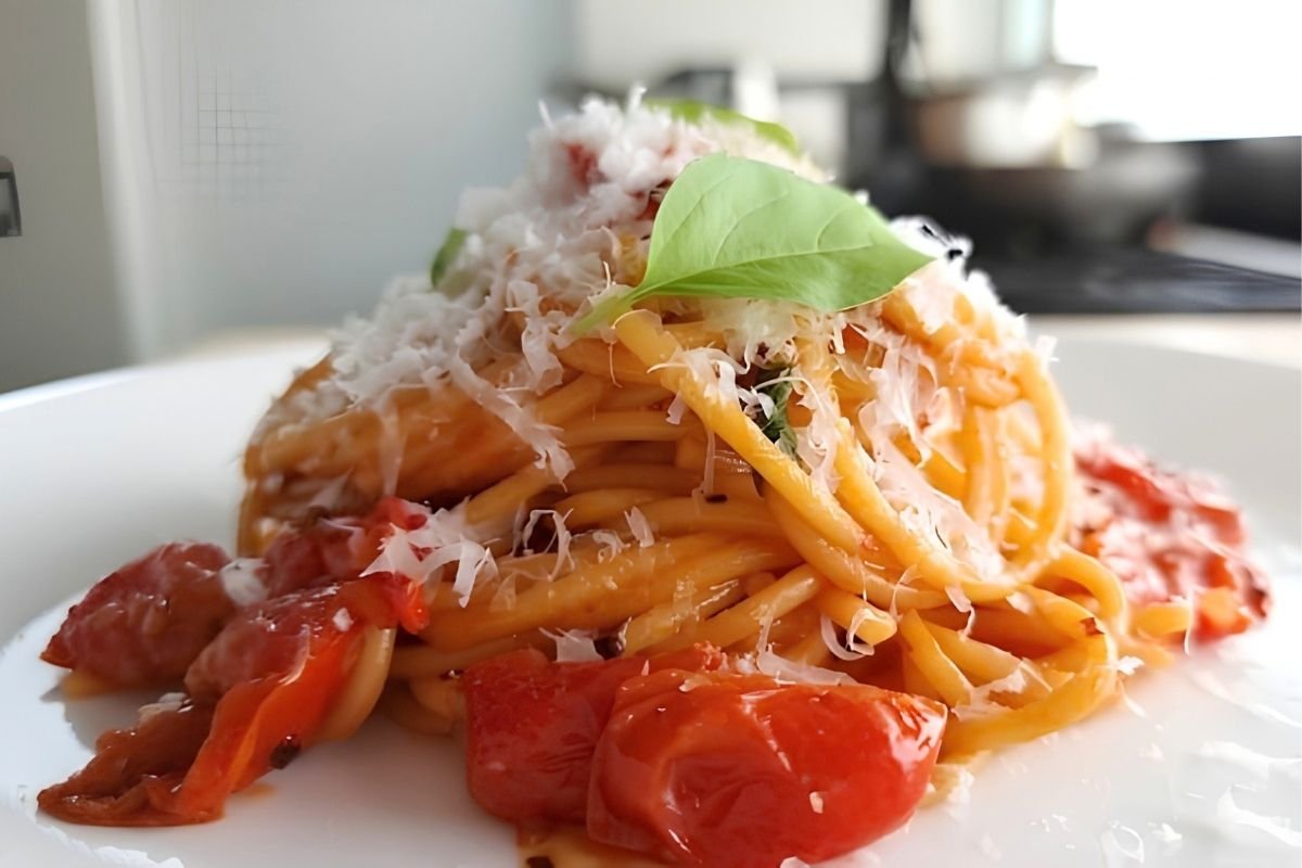spaghetti with roasted cherry tomatoes, grated parmesan and fresh basil on a white plate